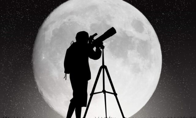 Siluett av person som tittar i tubkikare med månen som bakgrund